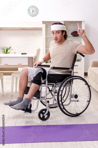 Injured young man doing exercises at home 