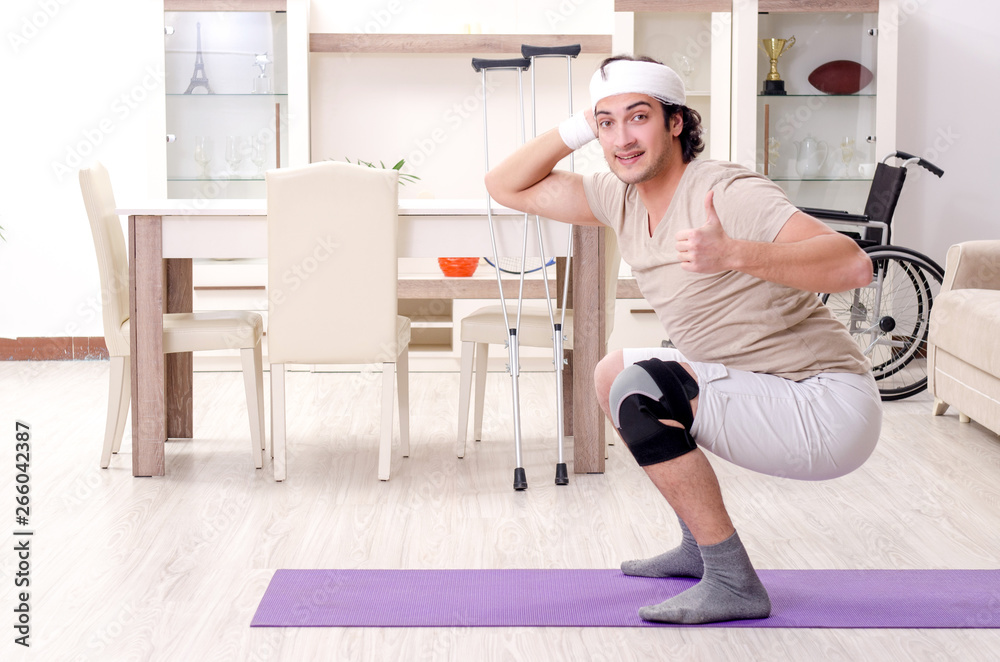 Injured young man doing exercises at home Injured young man doing exercises at home