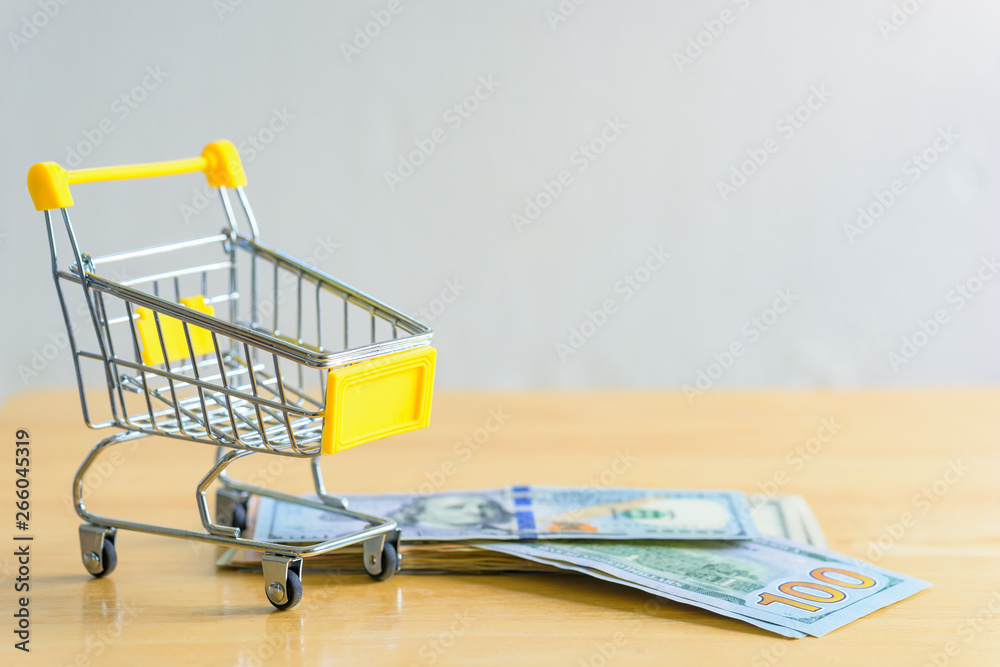 Dollar banknotes and trolley on a table, online shopping concept.