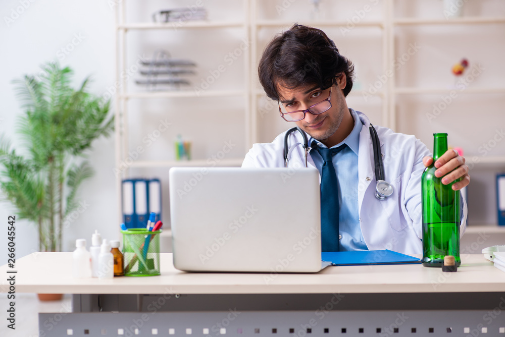Young male doctor drinking in the office 