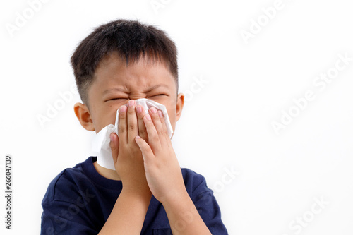 Canvas Print Sick little Asian boy using paper tissues while sneezing.
