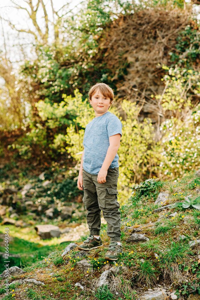 Cute little boy playing in summer park, green nature background, wearing blue t-shirt and khaki trousers Cute little boy playing in summer park, green nature background, wearing blue t-shirt and khaki trousers