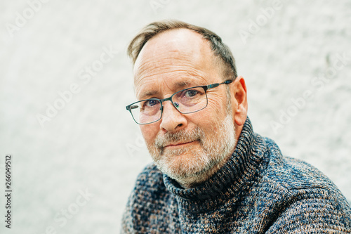 Outdoor portrait of 50 year old man wearing brown pullover and eyeglasses