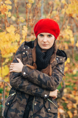 Young woman hiking in Lavaux vineyards in autumn, wearing warm military jacket and red beret