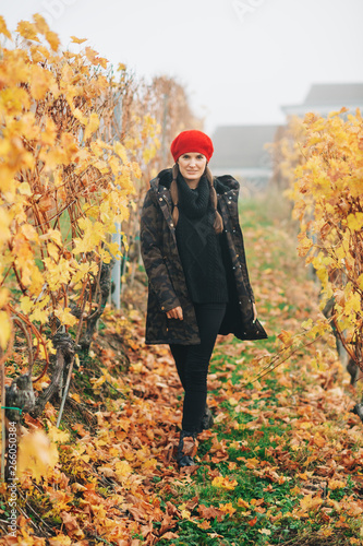 Young woman hiking in Lavaux vineyards in autumn, wearing warm military jacket and red beret © annanahabed