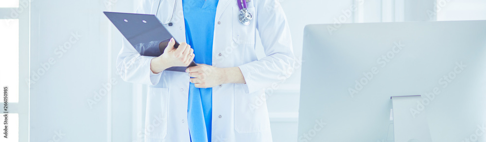 Woman doctor standing with folder at hospital Woman doctor standing with folder at hospital