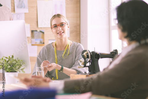 Female dressmaker is communicating with the potential client about custom-made dress in the sewing workshop photo