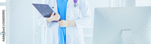 Woman doctor standing with folder at hospital