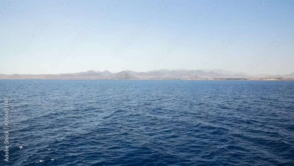 Small island with large mountains under blue sky Small island with large mountains under blue sky