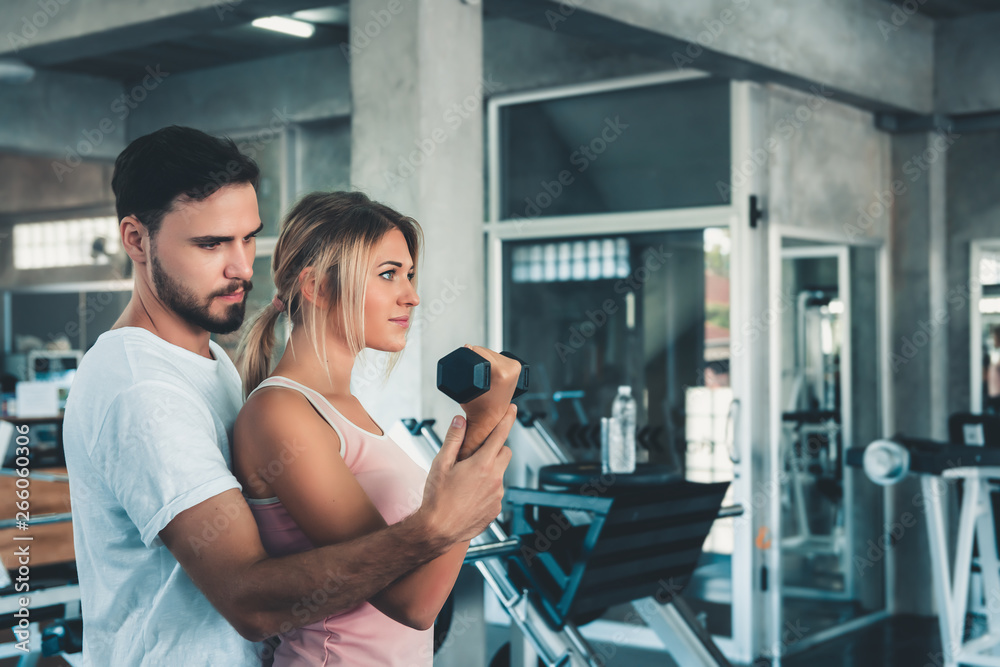 Portrait of Sporty Couple Love Exercised in Fitness Training With Dumbbell Equipment., Young Couple Caucasian are Working Out and Training Together in Gym Club. Sport Exercising and Healthy Concept Portrait of Sporty Couple Love Exercised in Fitness Training With Dumbbell Equipment., Young Couple Caucasian are Working Out and Training Together in Gym Club. Sport Exercising and Healthy Concept