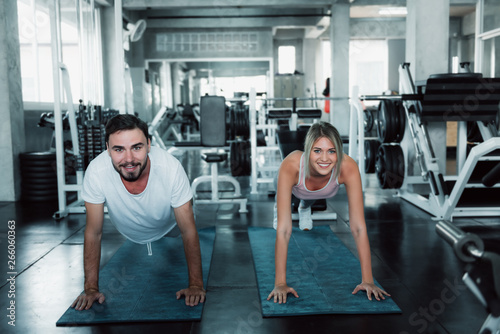 Sporty Couple are Push-Up Exercising in Fitness Gym.  Portrait of Young Couple Working Out Exercised Pushing-Ups Together on Sport Equipment Background.  Healthcare and Leisure Activities Concept.