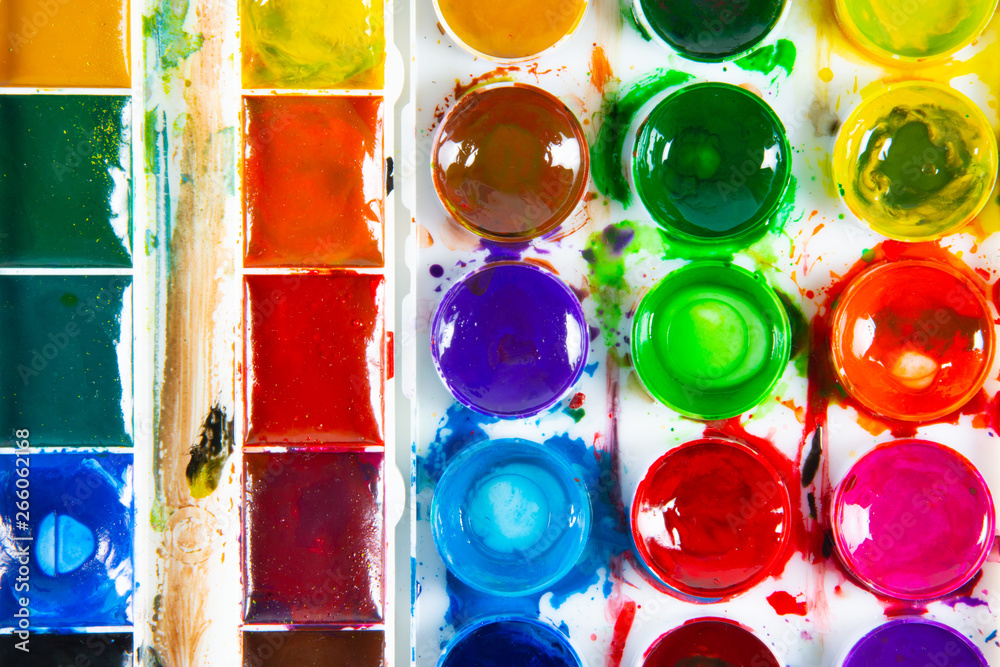 A set of children's paints in round, rectangular forms close-up. Original creative background