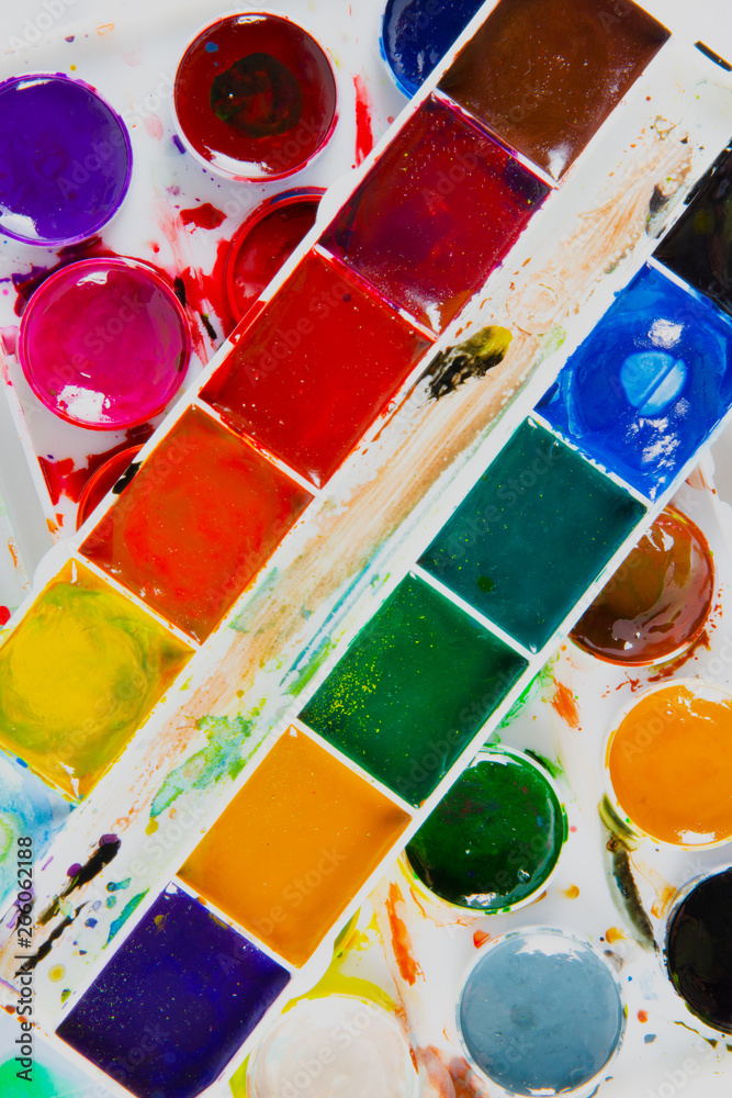 A set of children's paints in round, rectangular forms close-up. Original creative background