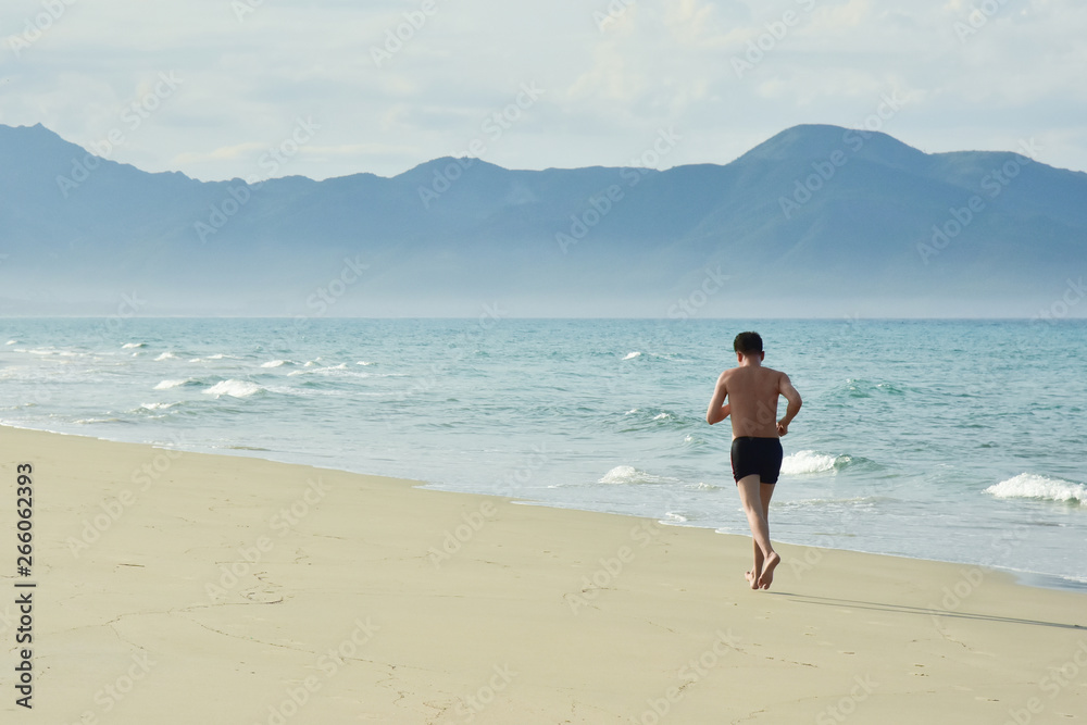 A man performs a morning workout. Running along the sandy beach along the coastline. Copy space for text. Vietnam