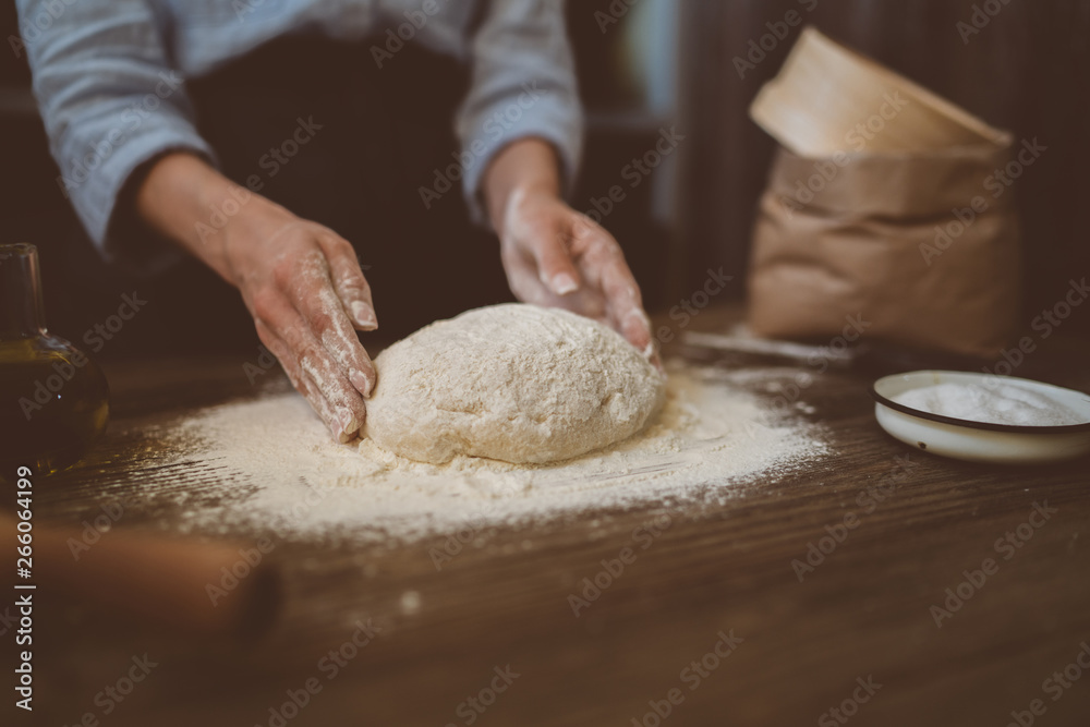 Female hands with dough in ball shape. Basic homemade dough with ingredients on wooden table with natural light. Home healthy food. Low key shot, close up on hands, some ingredients around on table. Female hands with dough in ball shape. Basic homemade dough with ingredients on wooden table with natural light. Home healthy food. Low key shot, close up on hands, some ingredients around on table.