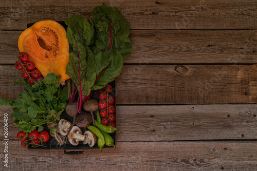 Autumn concept with seasonal vegetables for Thanksgiving Day. Fresh vegetables on dark table. Healthy eating. Squash, bell peppers and onions. Recipes or menu card. Flat lay, copy space. Toned image.