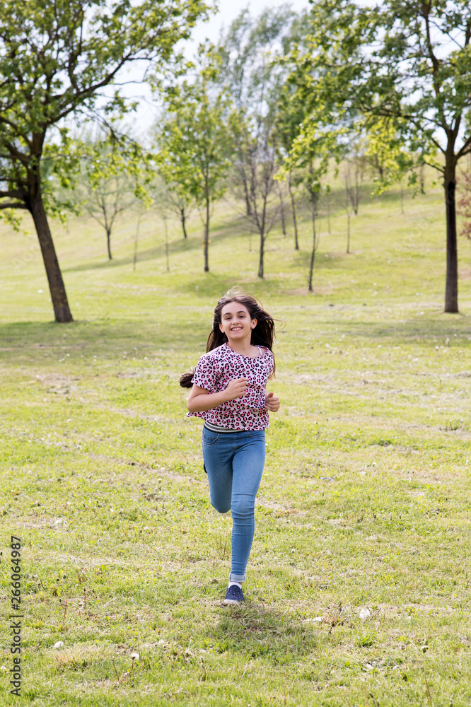 Fit athletic young girl running through a park