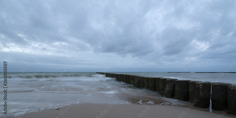 Sunset on the beach with waves against a dramatic blue cloudy sky, baltic sea, Usedom, Germany
