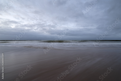 Sunset on the beach with waves against a dramatic blue cloudy sky, baltic sea, Usedom
