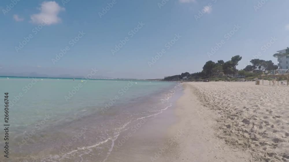 andando por la orilla de la playa en mallorca en un dia soleado con el mar en calma y las olas rompiendo en la orilla andando por la orilla de la playa en mallorca en un dia soleado con el mar en calma y las olas rompiendo en la orilla