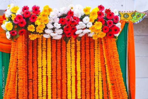 strings of marigold flower with colorful daisies as background at a wedding and engagement function. photo