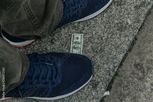 Large sneaker and small bill lie on granite step