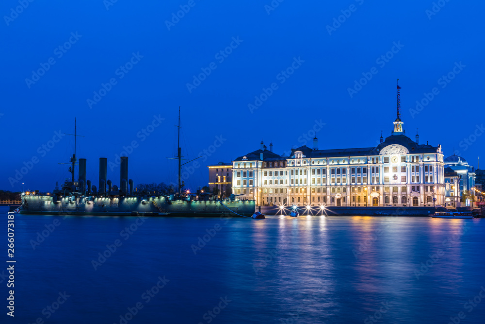 Petersburg, Russia - May 4 2019: Russian cruiser Aurora in the mouth of Neva river in Petersburg on the background of Nakhimov Naval School in the evening