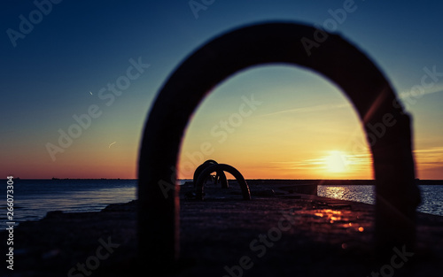 beautiful sunset on the sea. frame in frame. sunset through the iron bracket.