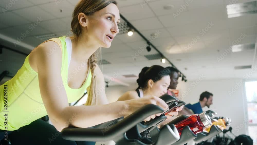 Very fit Caucasian woman and her friends on fitness bike in gym Very fit Caucasian woman and her friends on fitness bike in gym
