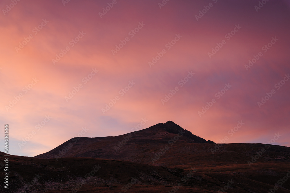 Orange scenic sky at sunset in the mountains. Clouds illuminated by the setting sun Orange scenic sky at sunset in the mountains. Clouds illuminated by the setting sun