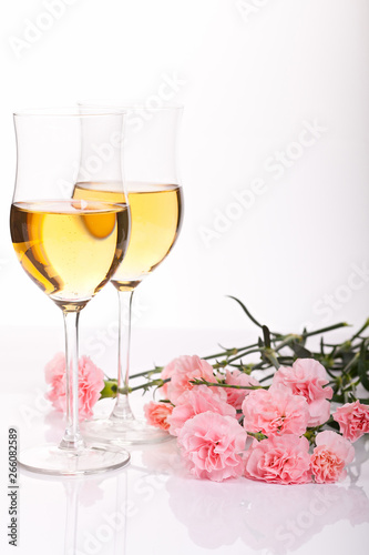 Two glasses with a drink and flowers on a white background