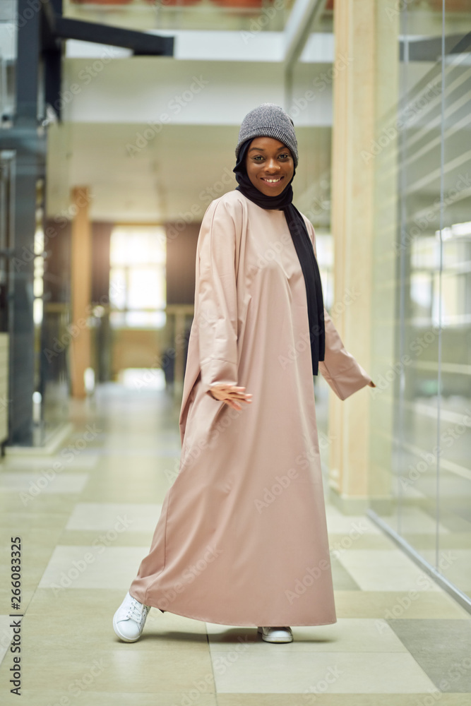 Beautiful young Muslim woman of african ethnicity dressed in pink long