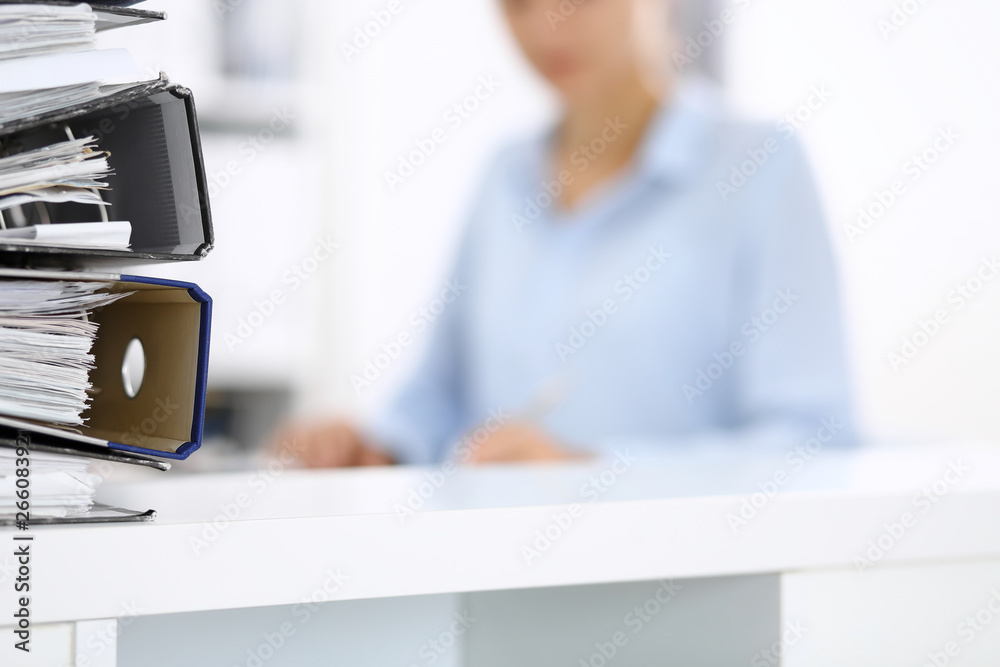 Binders with papers are waiting to be processed by business woman or bookkeeper back in blur. Internal Audit and tax concept