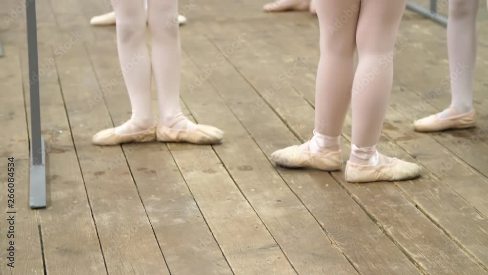 closeup , Young ballerina legs in ballet shoes, pointes, in beige leotards, perform exercises near barre, on an old wooden floor in a ballet school, during ballet lesson closeup , Young ballerina legs in ballet shoes, pointes, in beige leotards, perform exercises near barre, on an old wooden floor in a ballet school, during ballet lesson