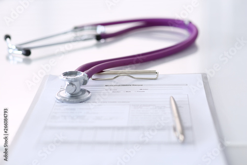 Medication history record form lying on table with stethoscope and silver pen. Medicine or pharmacy concept. Medical tools at doctor working table