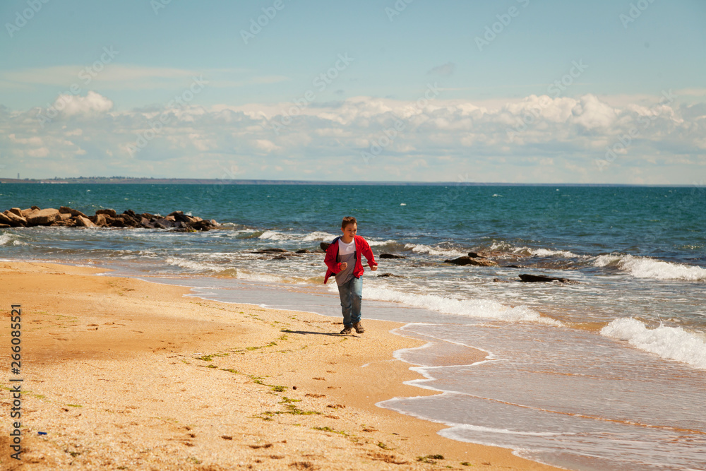 Nine year old boy runs along the seashore Nine year old boy runs along the seashore