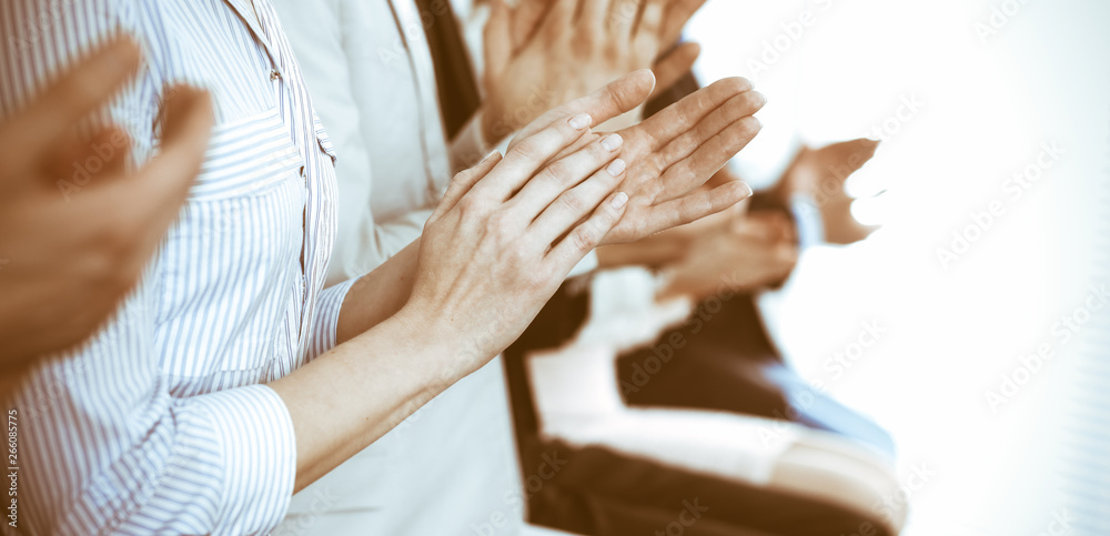 Obraz premium Business people clapping and applause at meeting or conference, close-up of hands. Group of unknown businessmen and women in modern white office. Success teamwork or corporate coaching concept