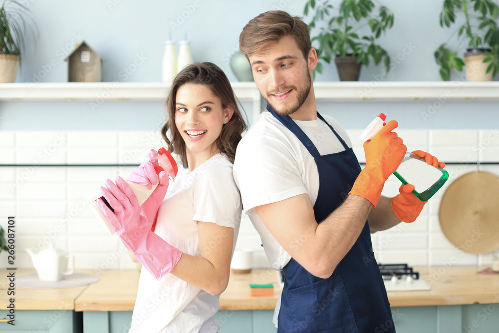 © ty - Young happy couple is having fun while doing cleaning at home.