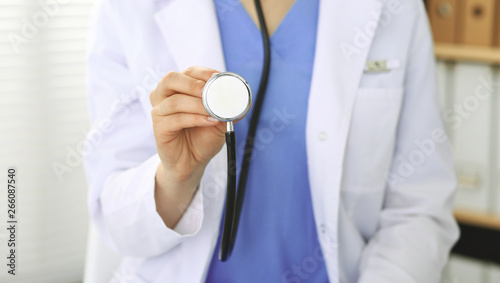 Unknown doctor woman holds stethoscope head, close-up. Physician ready to examine and help patient. Helping and insurance in health care, best treatment and medicine concept