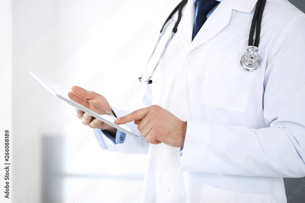 Doctor man using tablet computer for network research or virtual disease treatment, hands close-up. Perfect medical service in clinic. Modern medicine, medic data and healthcare concepts Doctor man using tablet computer for network research or virtual disease treatment, hands close-up. Perfect medical service in clinic. Modern medicine, medic data and healthcare concepts