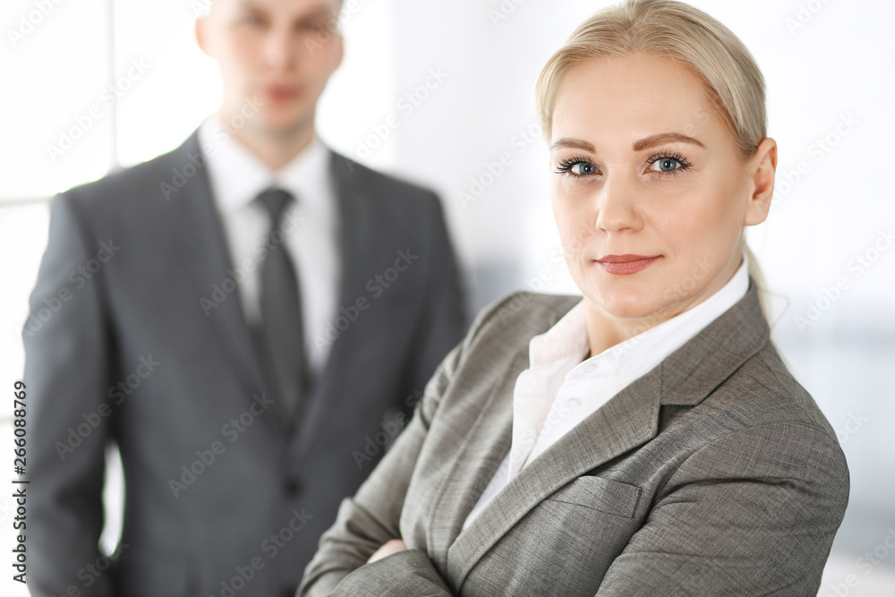 Business woman standing straight with colleague businessman in office, headshot. Success and corporate partnership concept Business woman standing straight with colleague businessman in office, headshot. Success and corporate partnership concept