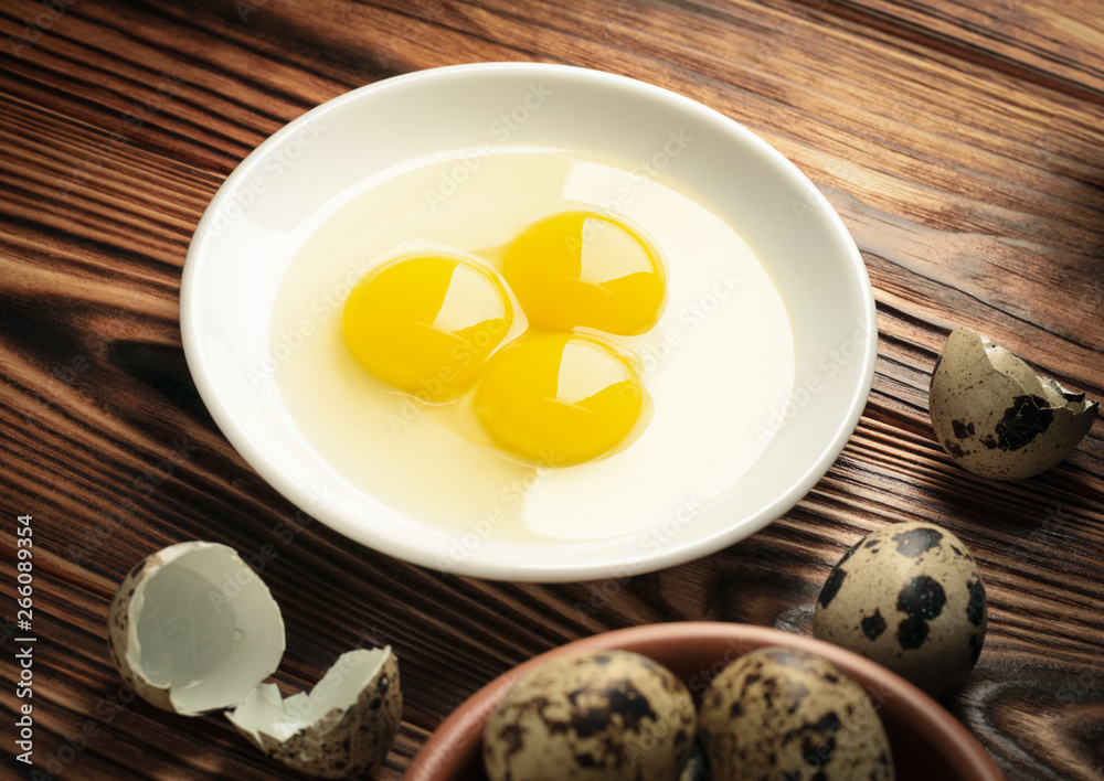 Quail eggs without shell on a white plate on a wooden background of burnt wood Quail eggs without shell on a white plate on a wooden background of burnt wood