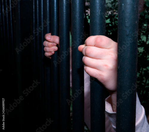 Hands of a refugee child on a steel fence