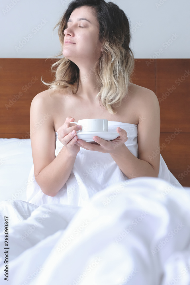 Beautiful young woman drinking her morning coffee in bed Beautiful young woman drinking her morning coffee in bed