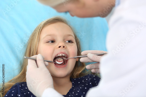 Little baby girl sitting at dental chair with open mouth during oral check up while doctor. Visiting dentist office. Medicine concept