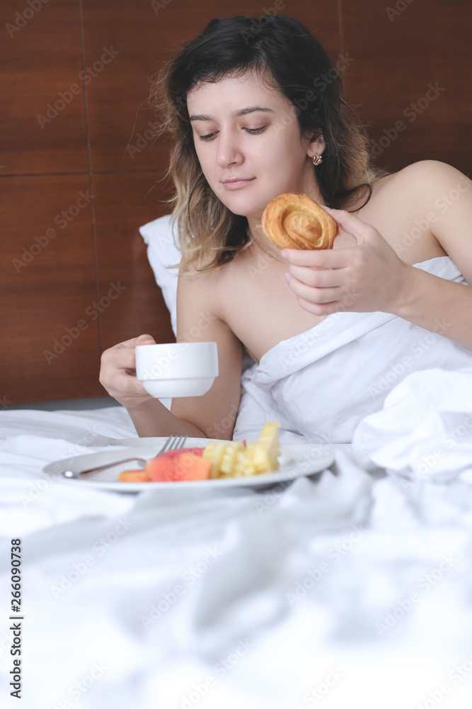 Young woman eating breakfast in bed. Lazy morning concept Young woman eating breakfast in bed. Lazy morning concept