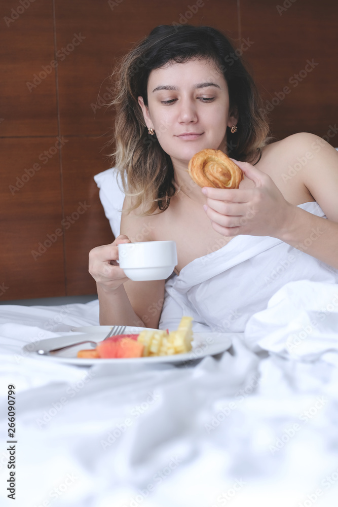 Beautiful young woman drinking her morning coffee in bed Beautiful young woman drinking her morning coffee in bed