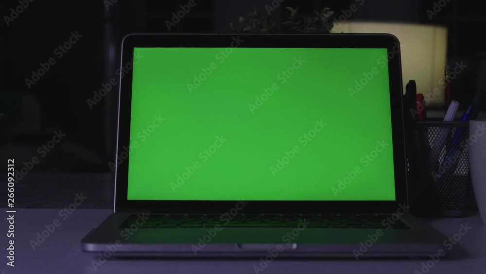 Laptop with green screen. Dark office. Dolly shot. Perfect to put your own image or video. Laptop with green screen. Dark office. Dolly shot. Perfect to put your own image or video.