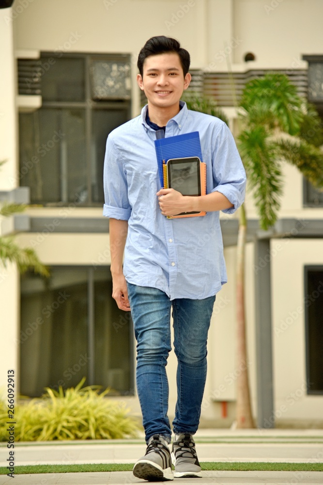 Fototapeta premium Smiling Handsome Asian Boy Student With Notebooks Walking