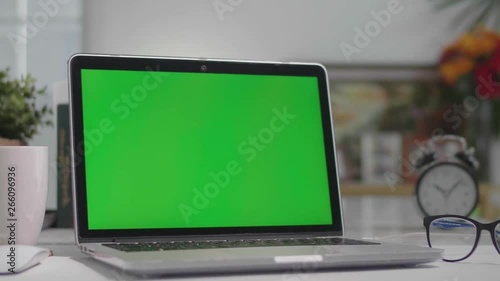 Woman working on the laptop computer with green screen at home. Chroma key. View from the back. 